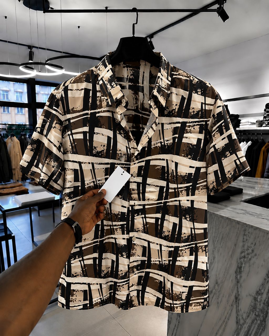 Patterned shirt with a hand holding a phone in a store setting