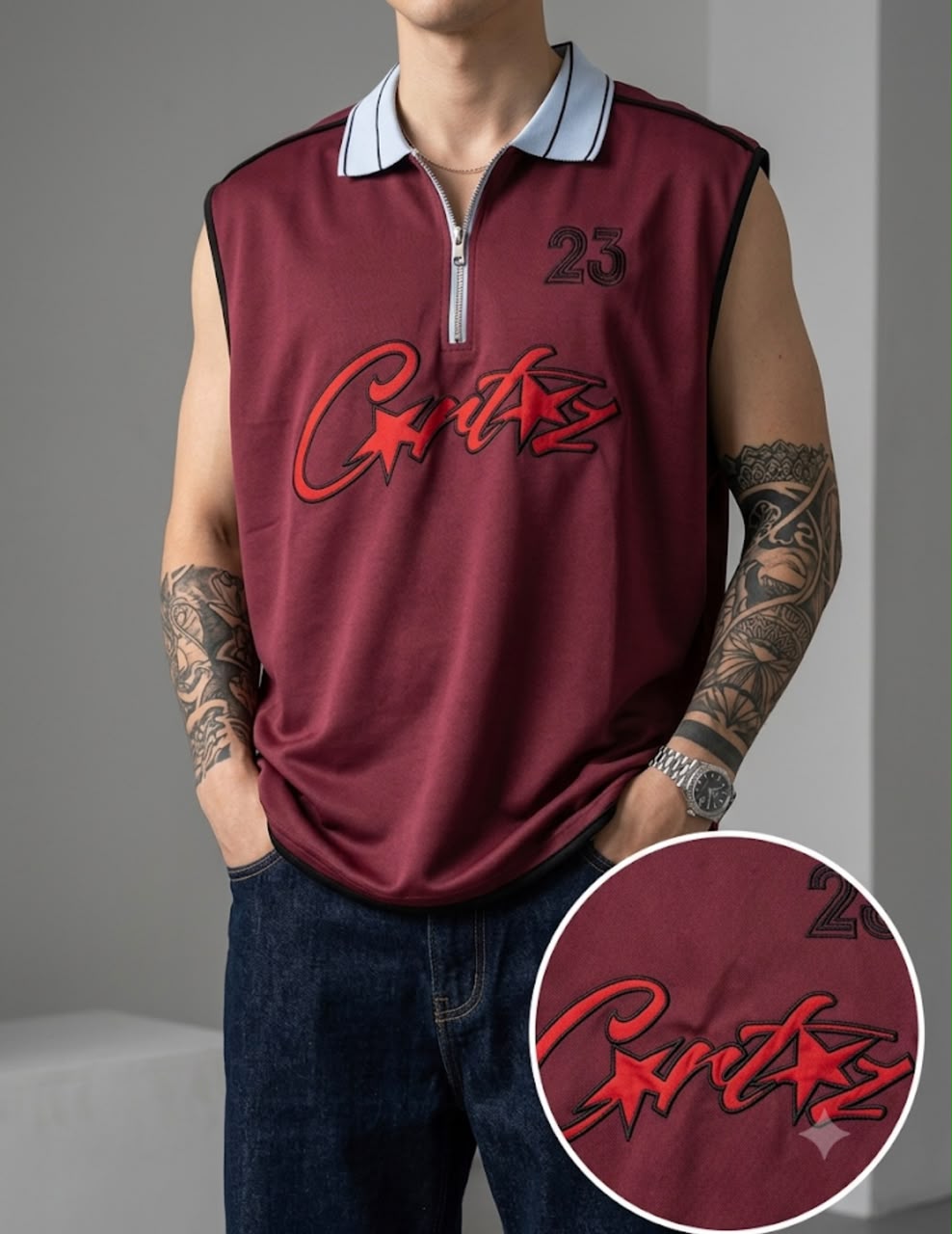 A man wearing a sleeveless maroon polo-style top with a half-zip collar, black trim, a red script logo across the chest, and the number 25 on the upper right chest. The image includes a circular inset showing a close-up of the chest graphic.
