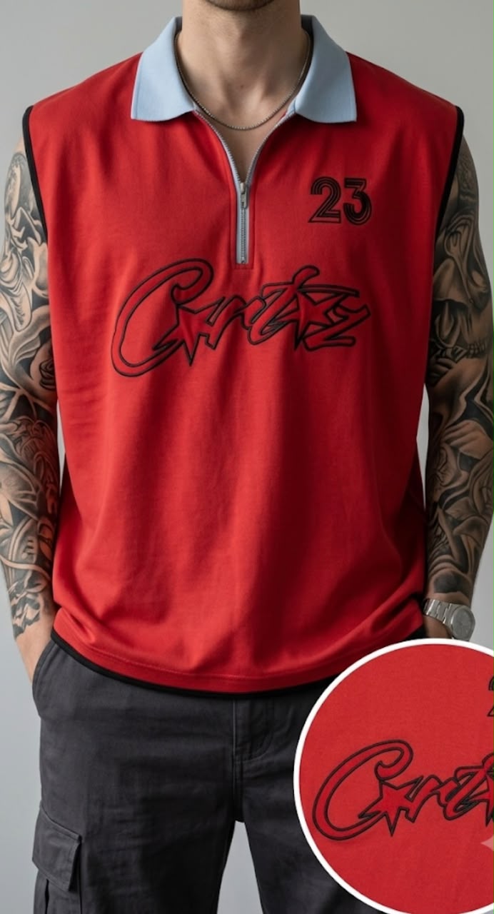 A red sleeveless quarter-zip polo shirt with a light blue collar, featuring a black script logo and the number '23' on the chest. The shirt is modeled by a tattooed man, and a circular inset shows a close-up of the black script logo on the red fabric.