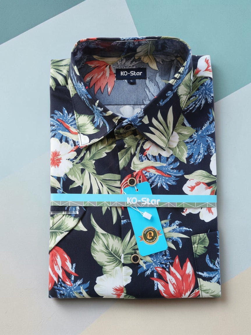 A folded men's button-up shirt by KO-Star featuring a vibrant tropical floral and leaf print on a dark navy base, with a light blue paper band and matching hangtag around the waist.